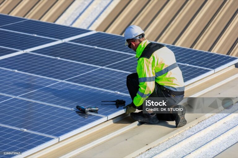 Monteur befestigt Photovoltaikmodule auf einem Dach